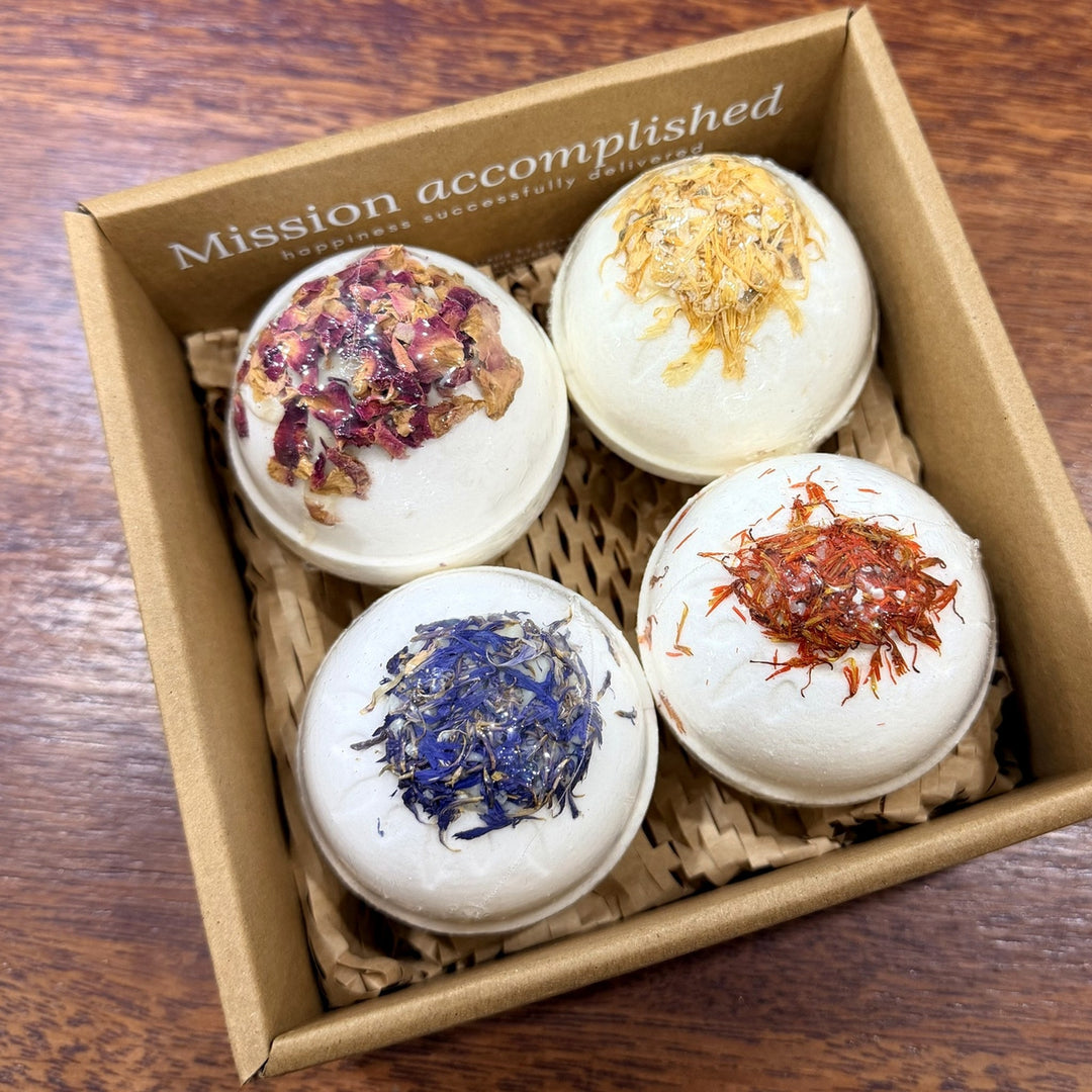 Four botanical bath bombs with dried flower toppings nestled in a kraft gift box