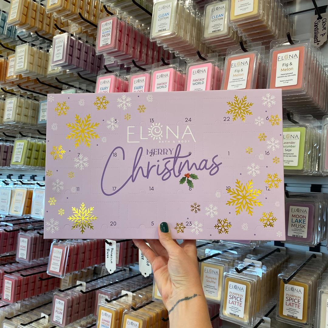 Hand holding a Christmas-themed product packaging in a store aisle with various products.